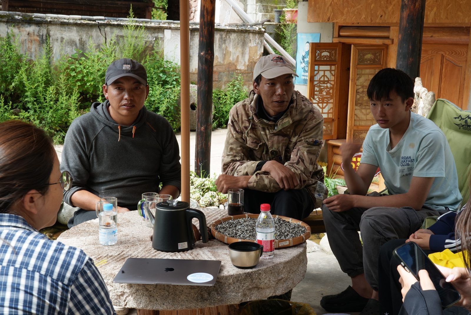 Villagers and volunteers recording an oral-history conversation in a courtyard