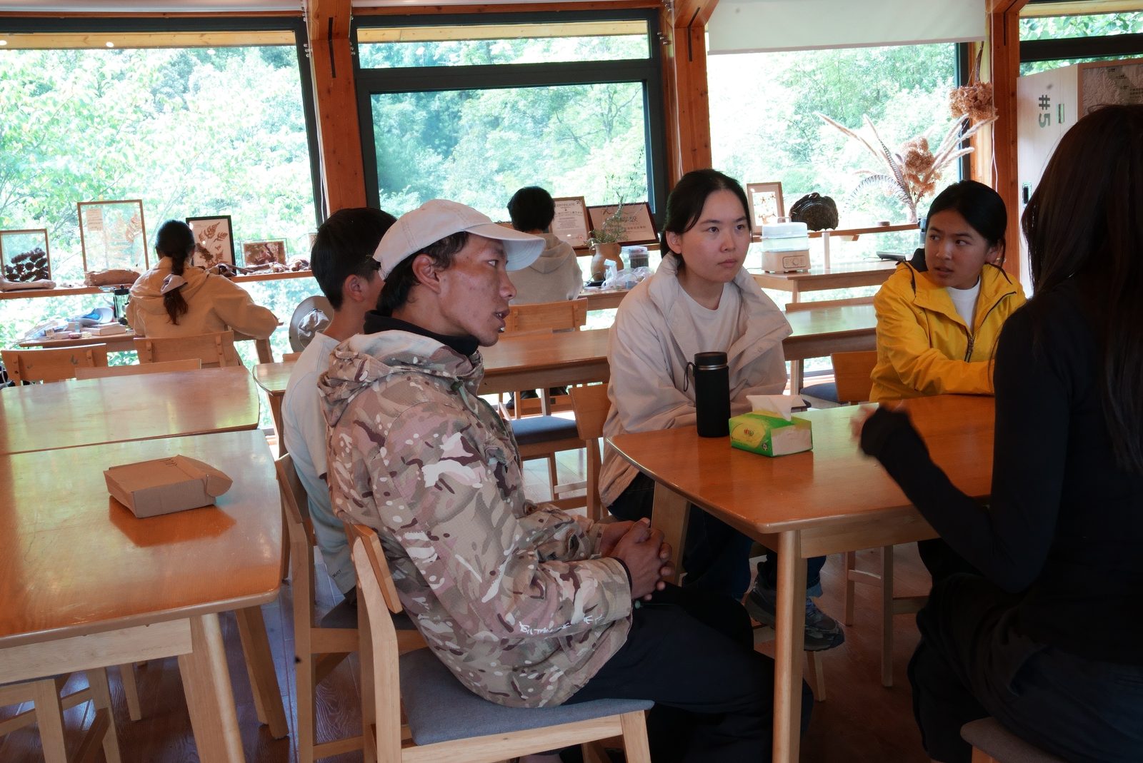 A group in conversation around wooden tables at the nature centre